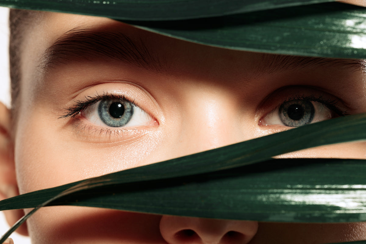 Close-up of a woman's eyes framed by green leaves.