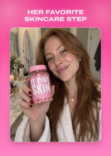 Woman holding an It Girl Skin bottle beside her face.